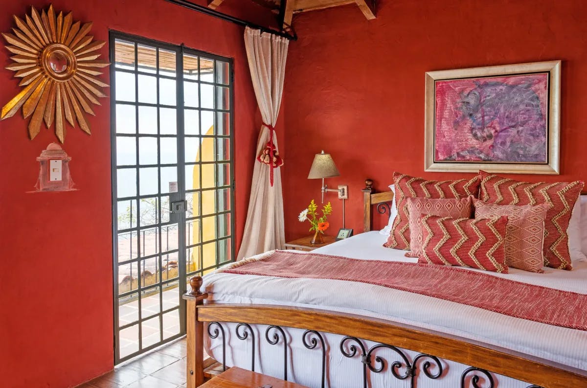 a stylish red-walled bedroom with a golden sun hanging on the wall