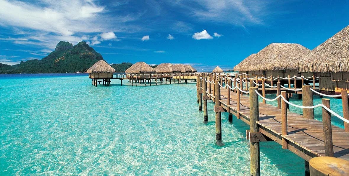 A group of bungalows above bright blue water during the daytime