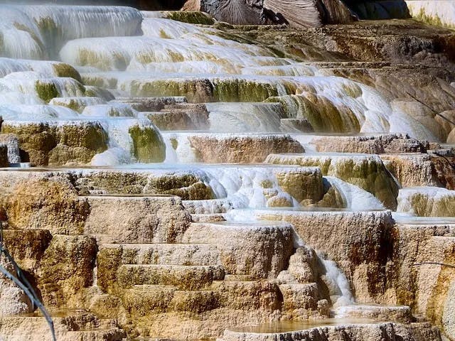 water falls in the middle of brown rocky mountain