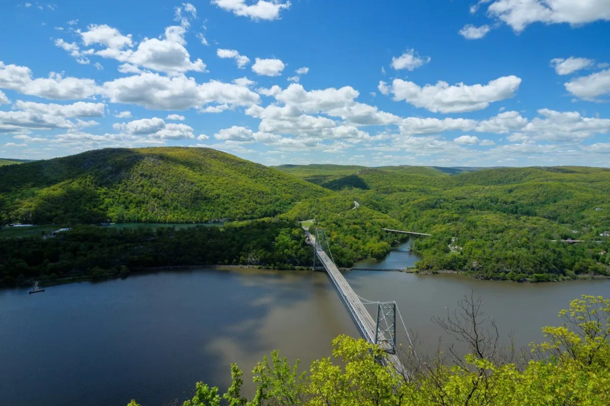 bridge spanning a river with mountains and blue sky