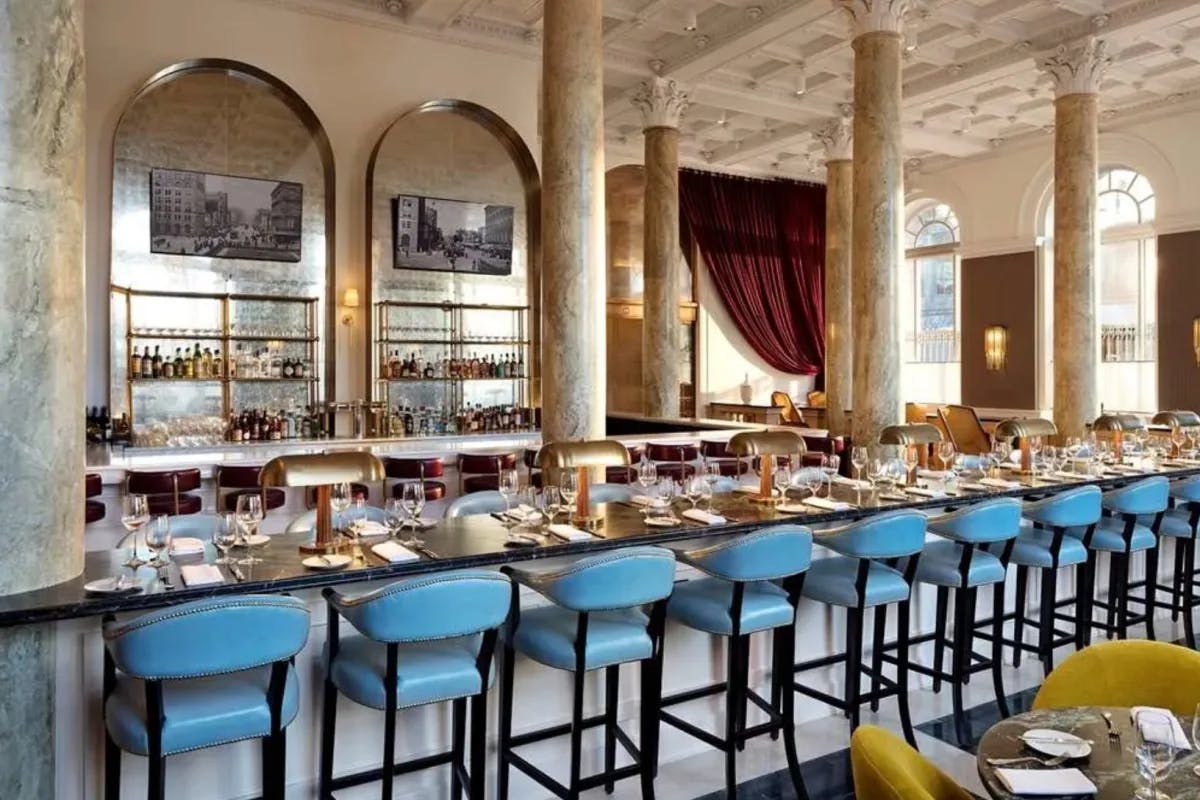 bar with blue leather stools and marble columns