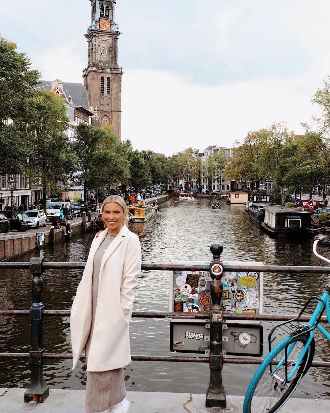 Travel advisor posing in a white coat on a canal