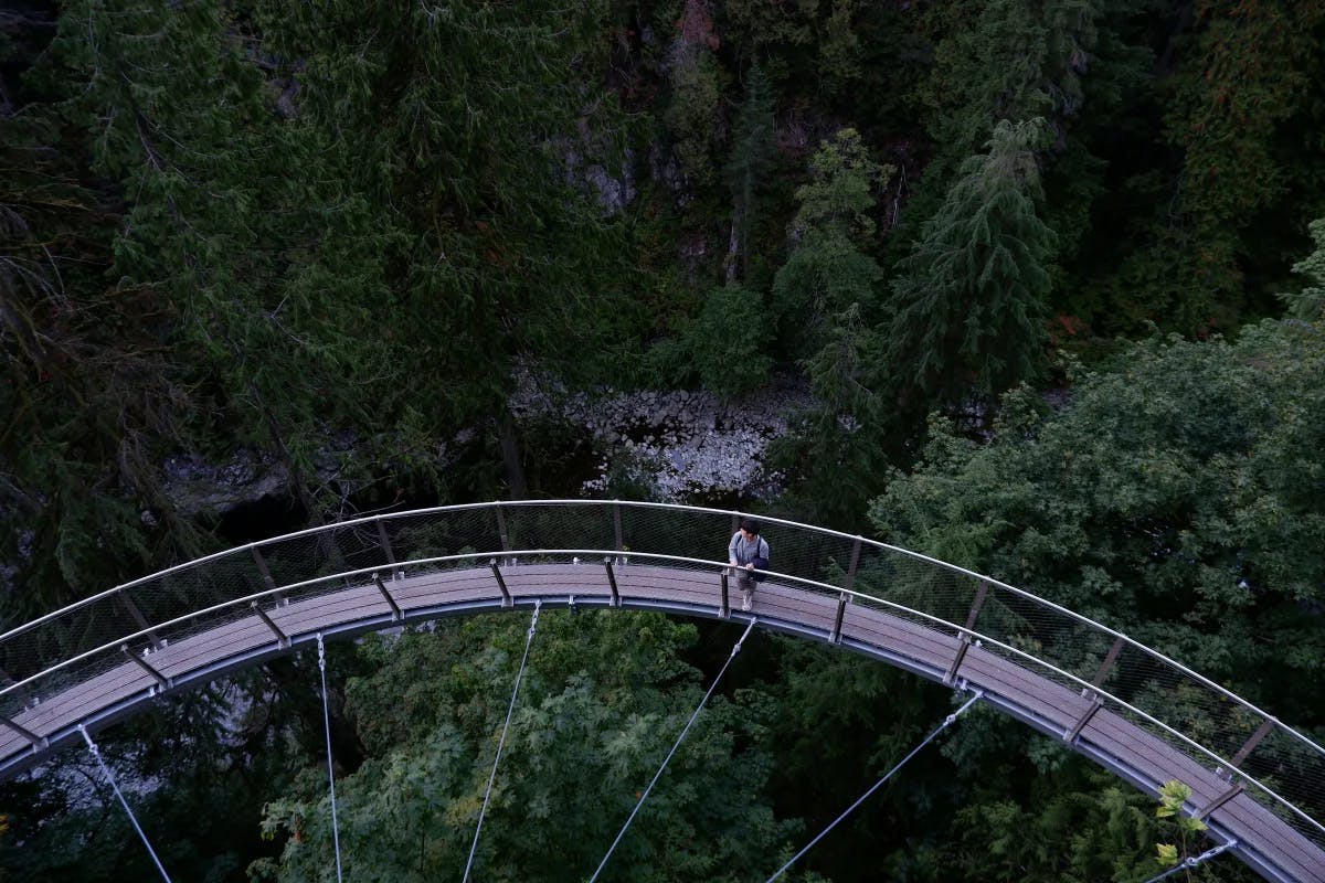 A person walking across the bridge at Capilano Suspension Bridge Park.