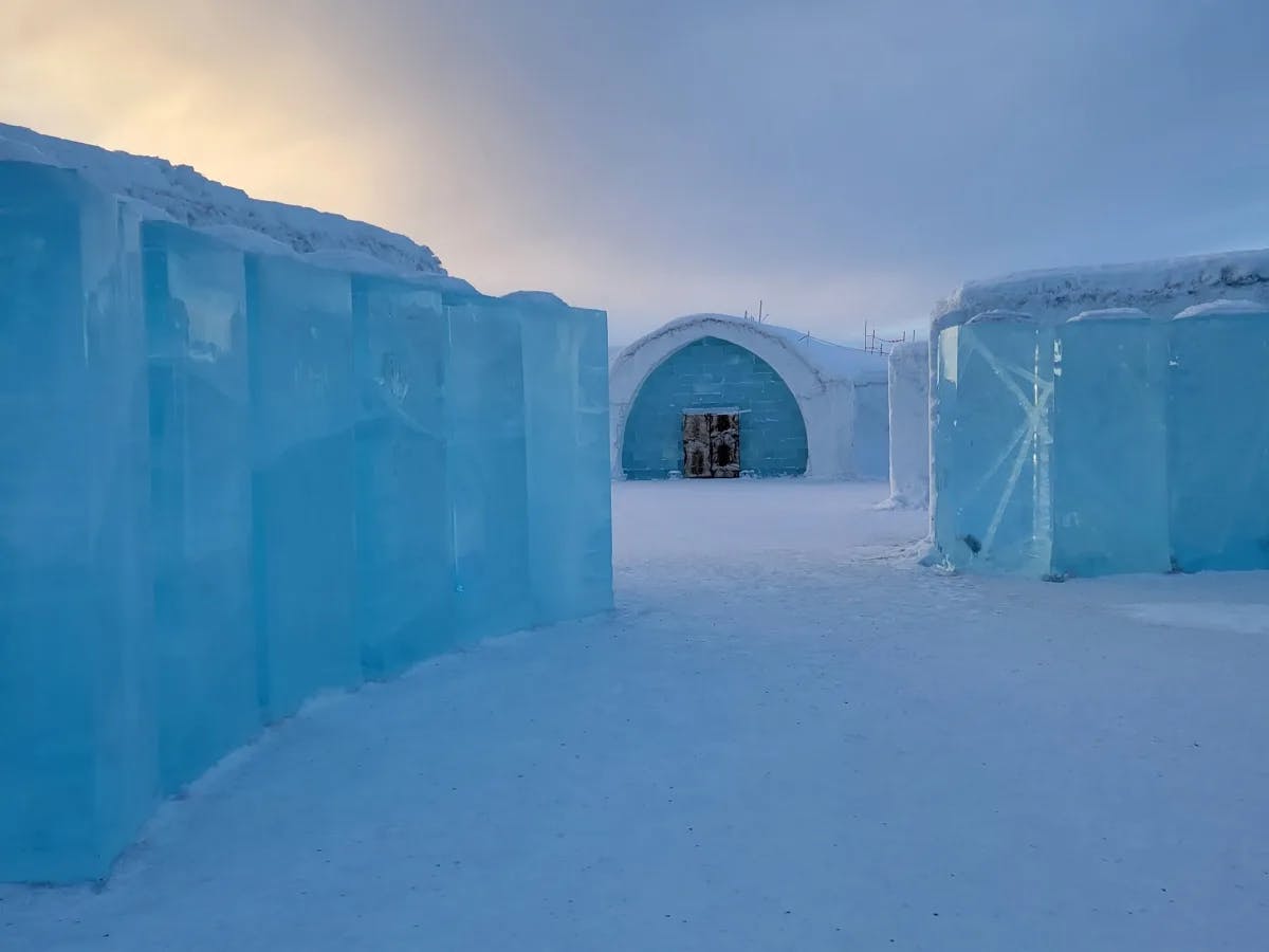 An igloo behind ice walls in an ice field at sunrise.