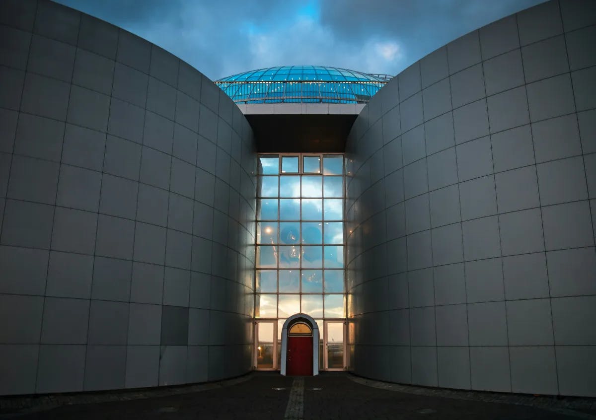 The exterior of the Perlan museum, with a large glass entryway between two rounded structures.