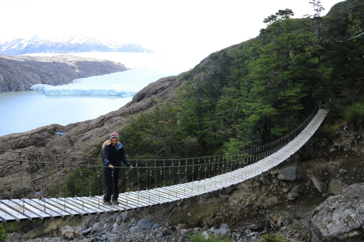 Advisor standing on suspension bridge between mountains.