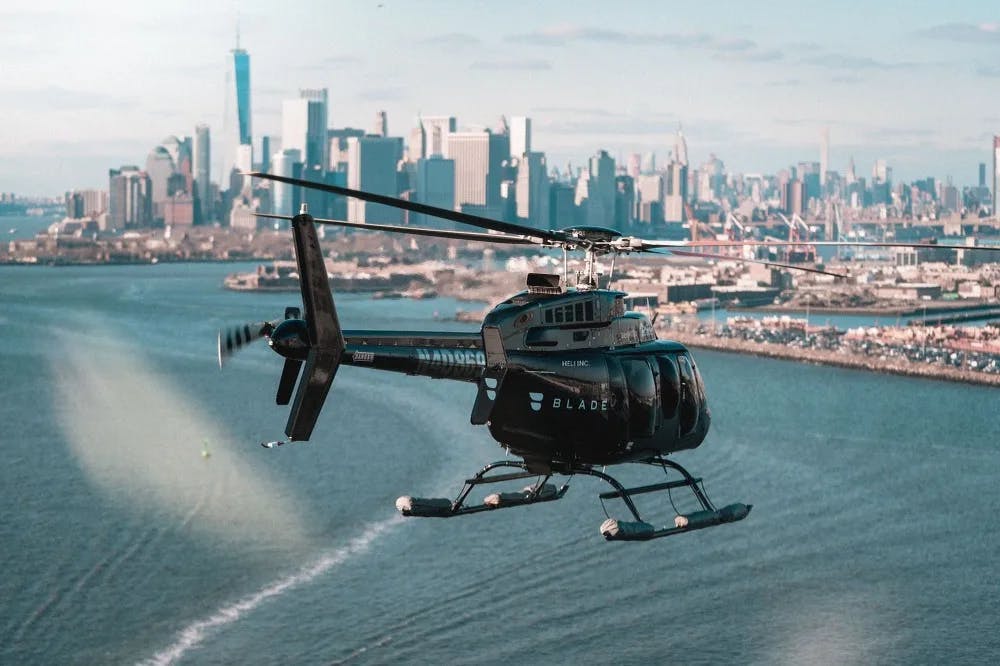 a black helicopter flies over a seaside city