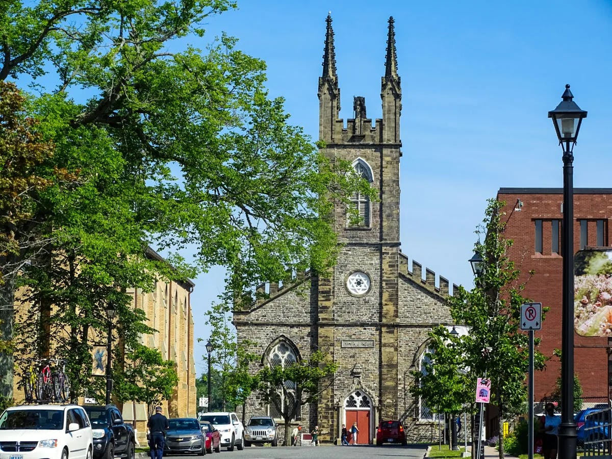 A stone church surrounded by trees at the end of a street in St. John.