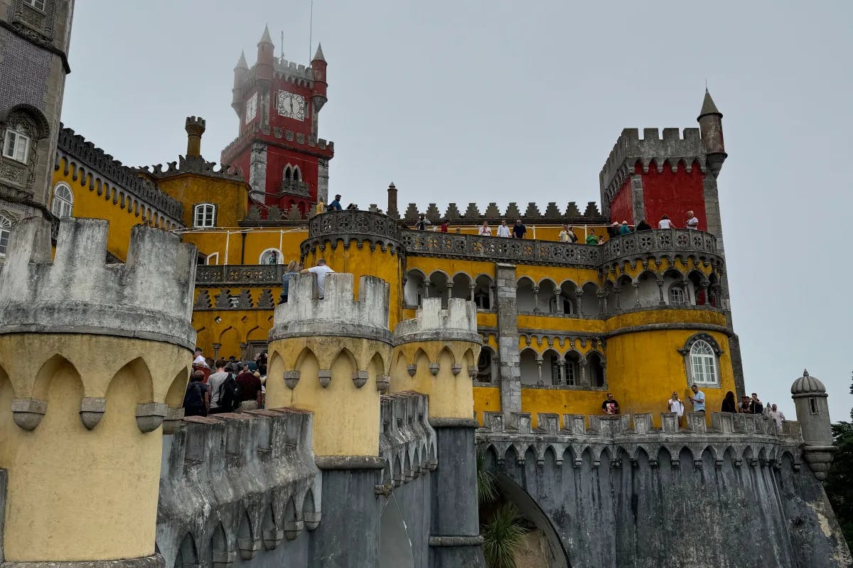 The National Palace of Pena stands on the top of a hill in the Sintra Mountains on a hazy day.