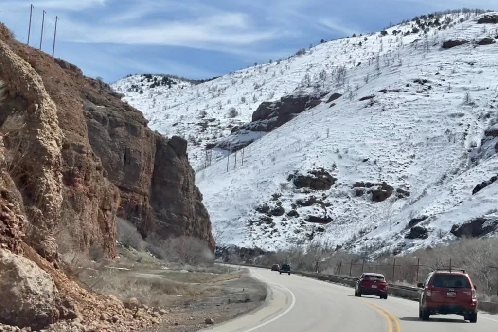 A picture of a car on a road between mountains during daytime