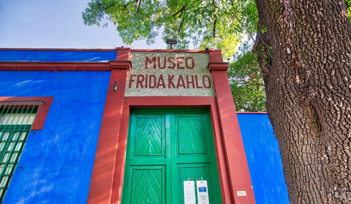 Entrance to Frida Kahlo's former home with cobalt blue walls and large emerald doors. 