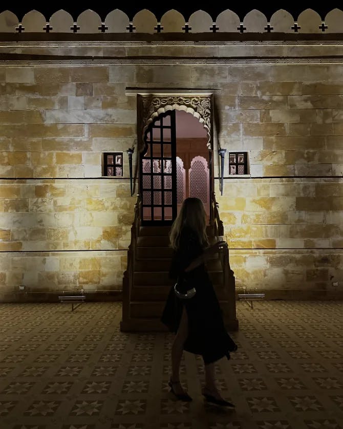 Advisor in silhouette on a street in front of a stone wall lit up at night