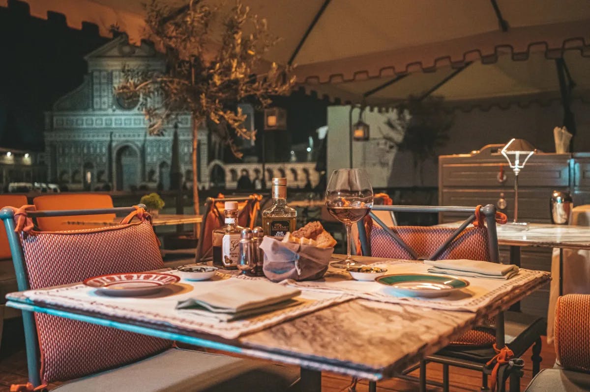 A fine dining table with wine bottles and a wine glass. 