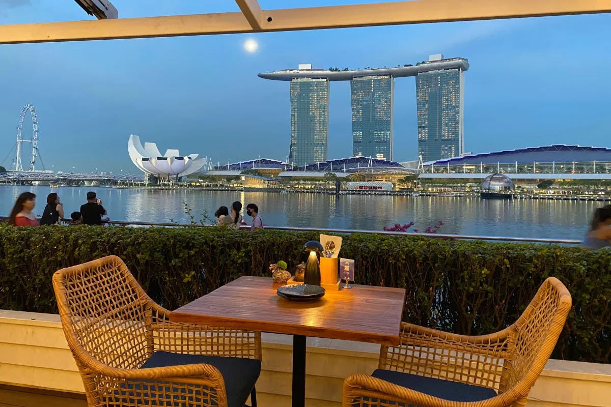 An outside dining area next to a body of water with a view of the city