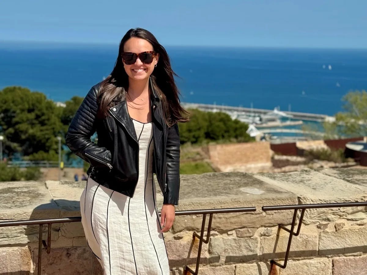 A woman in black jacket with ocean in the background.