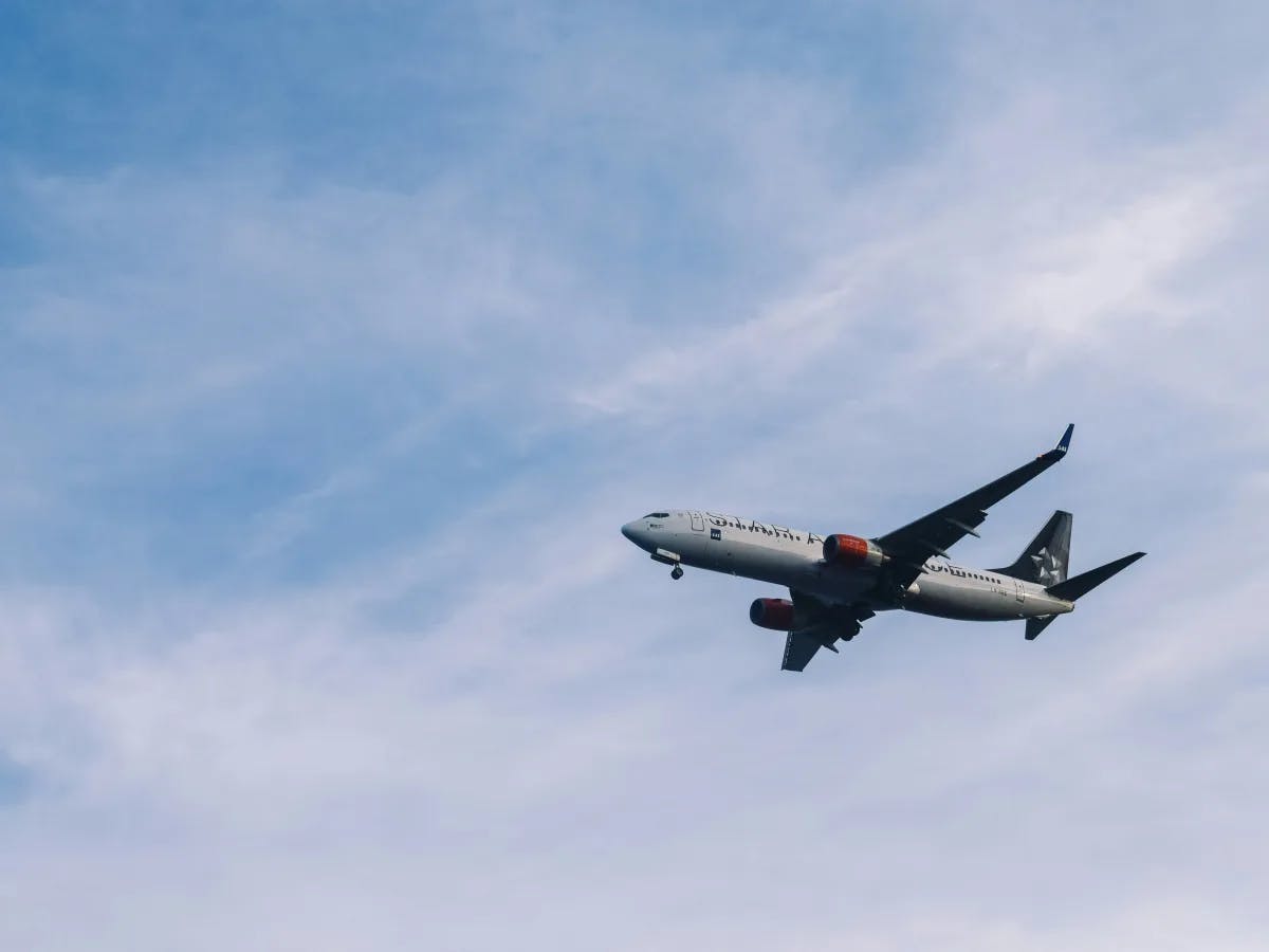 A commercial airplane flying in a clear blue sky with light clouds