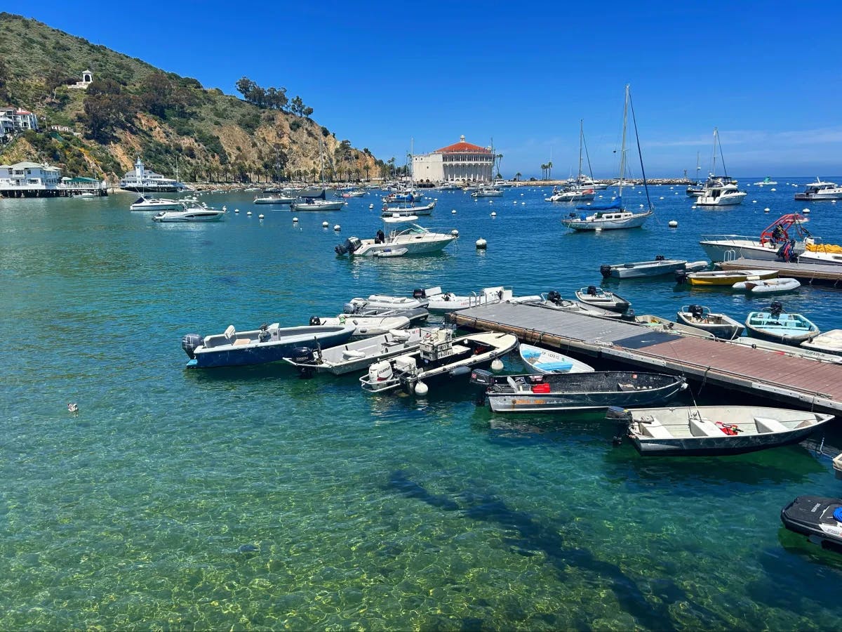 A boat harbor during the daytime with a view of the island's hills in the distance