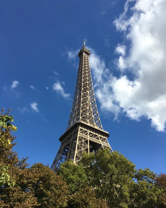 Low-angle view of the Eiffel tower and blue sky with white clouds