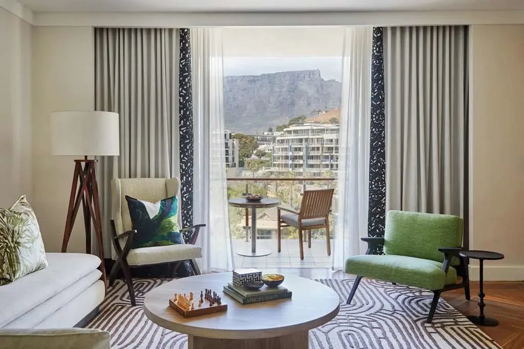 a green chair on a striped rug in a hotel room with views of a flat mountain