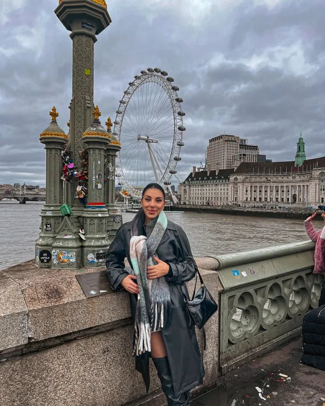 Samar Asfour posing in a beautiful city with a ferris wheel in the background. 