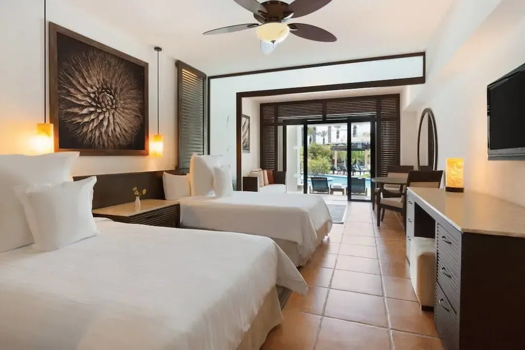 White twin beds, simple decor and a walkway that opens directly into the resort pool denote a room at Hyatt Ziva Los Cabos