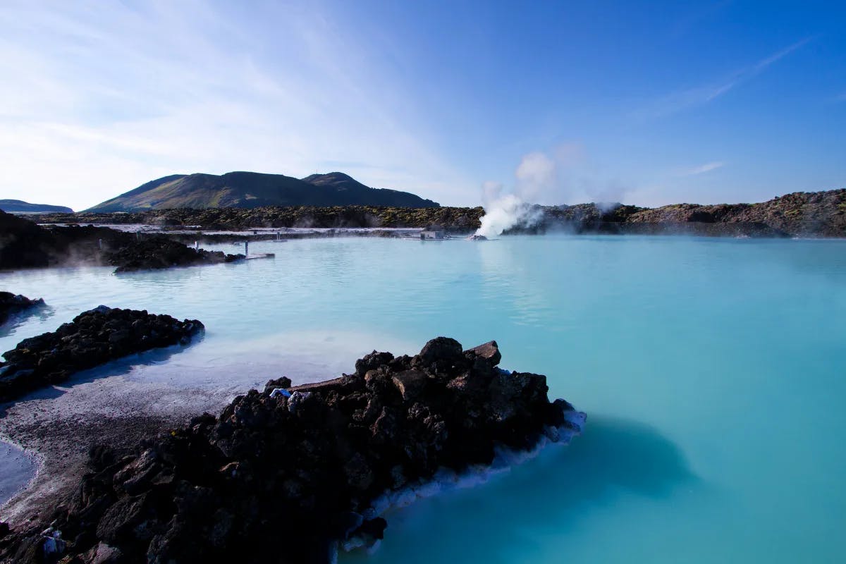 The blue lagoon in Iceland, with blue water between rocks on a clear day.