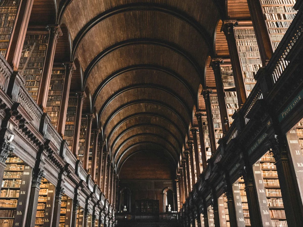 The image features a grand library with arched ceilings and wall-to-wall bookshelves filled with books, highlighting its vast collection and architectural elegance.