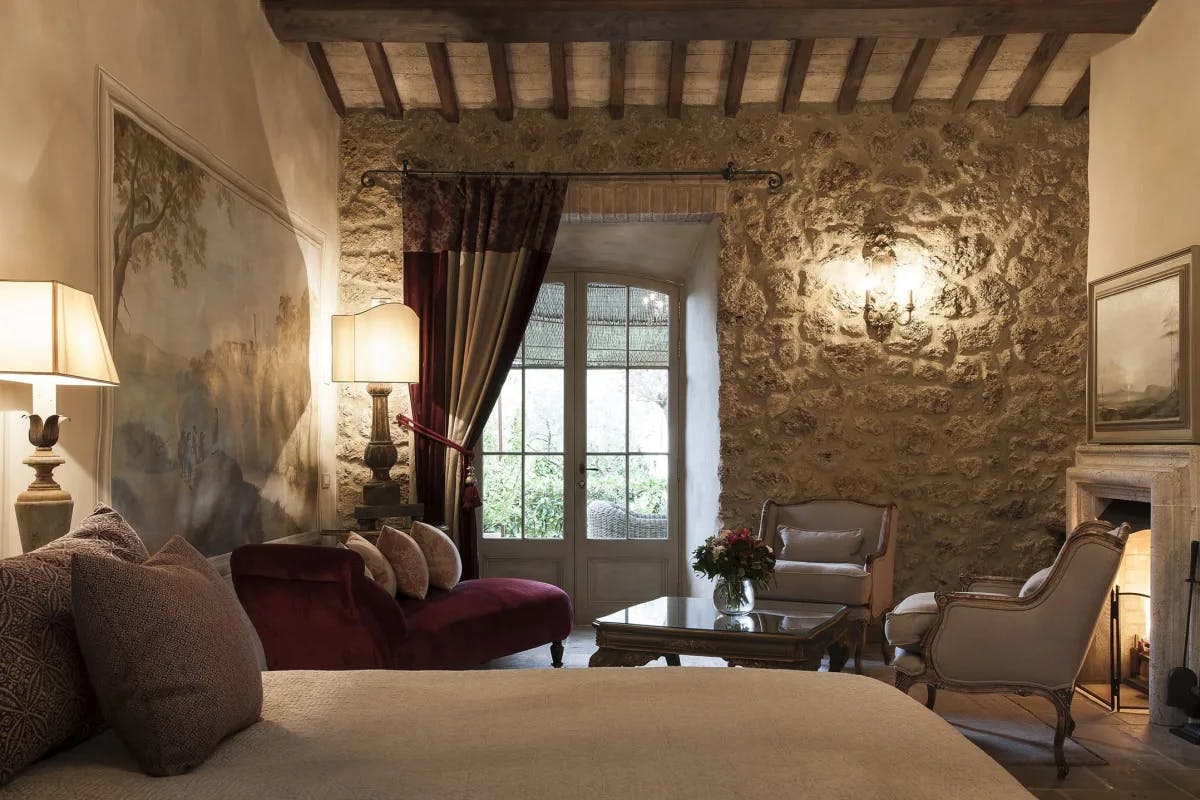 a luxe hotel room with a rustic rock wall and a stone fireplace