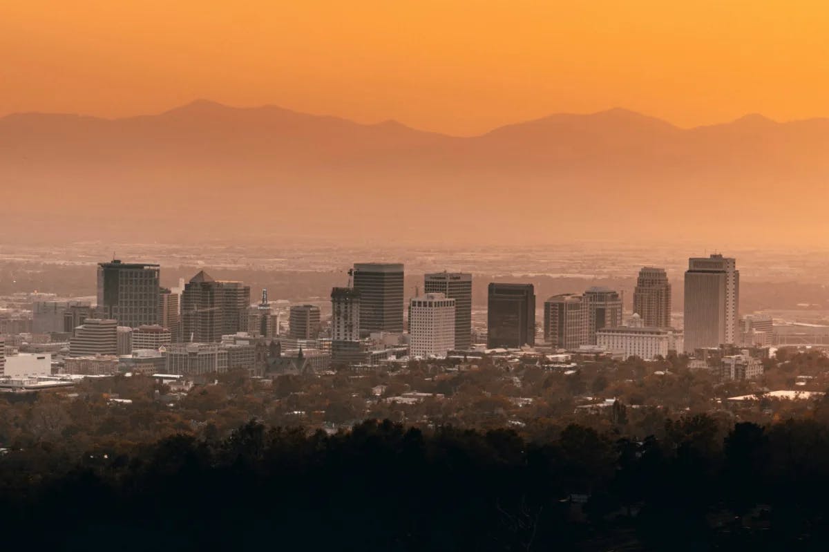 Skyline of city with buildings, mountains and a hazy orange sky. 