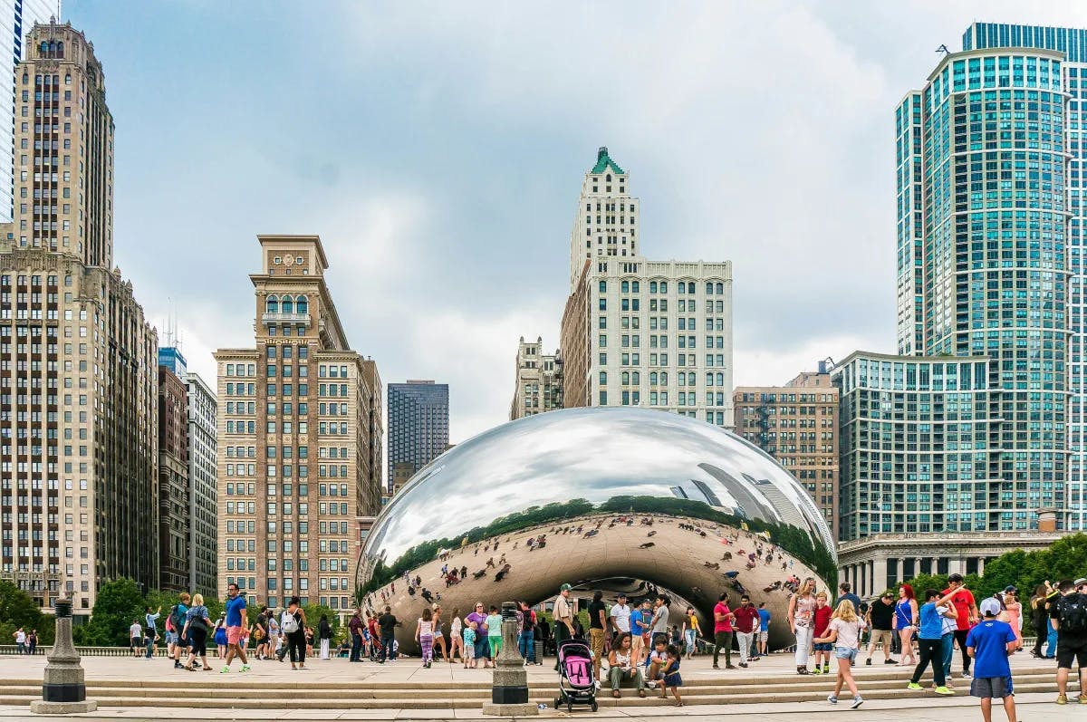 The metal Bean sculpture by city buildings during the daytime