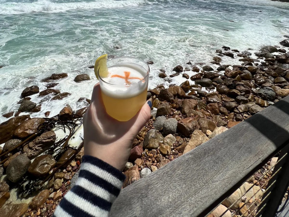 A hand outstretched over the water holding a drink