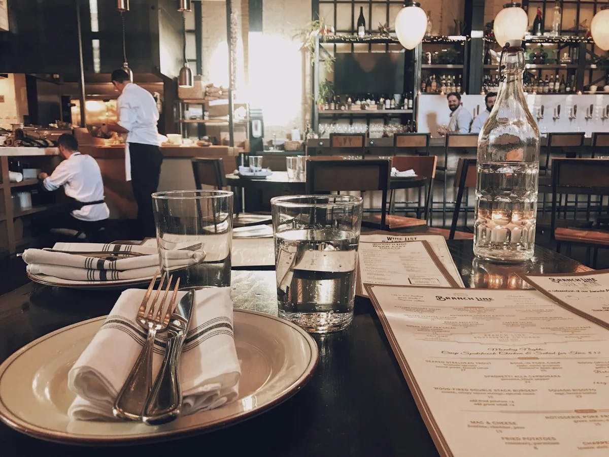 A restaurant table set for dining, complete with menus and glasses of water, with a black and white restaurant aesthetic.