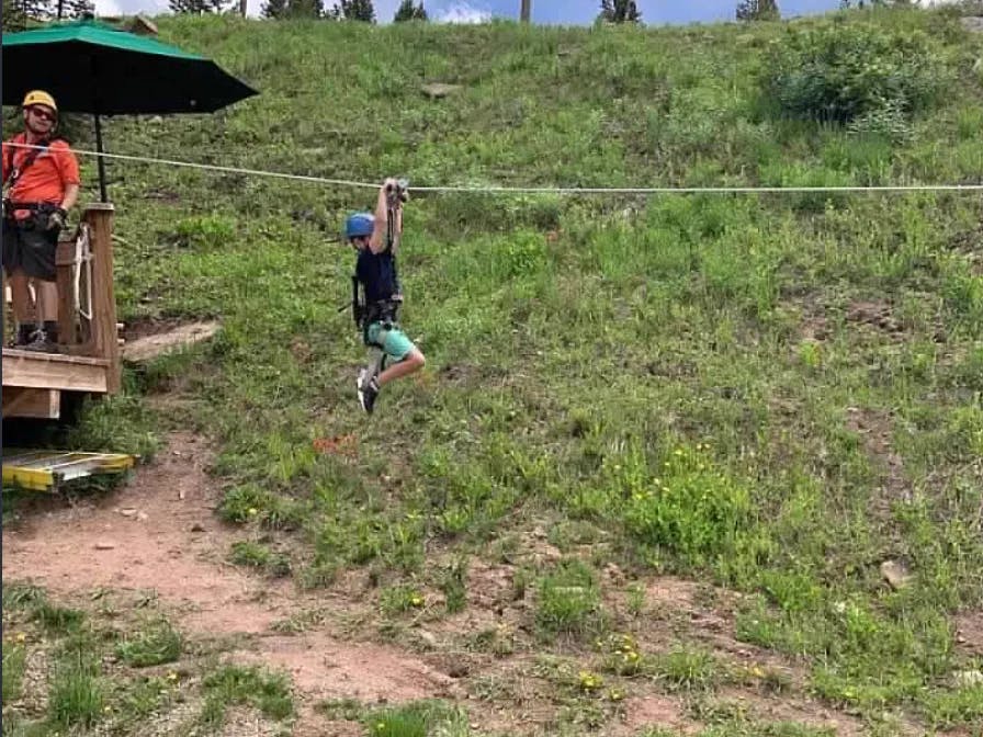 A thrilling moment of adventure as a person zip-lines over a verdant landscape.