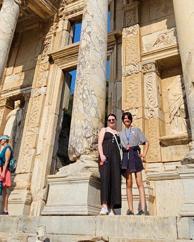 Travel advisor with a friend in front an old building with pillars. 