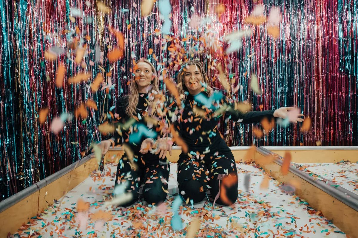 Girls having fun in a pool of confetti and smiling while laughing. 