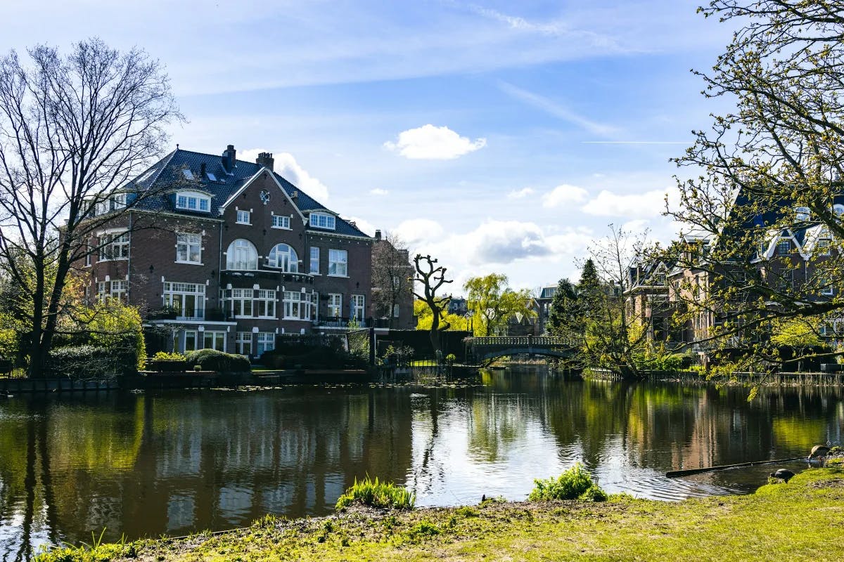 A large brick house behind a pond during the daytime