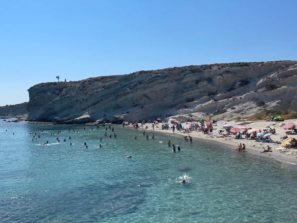 An aerial view of the beach filled with people during the daytime.