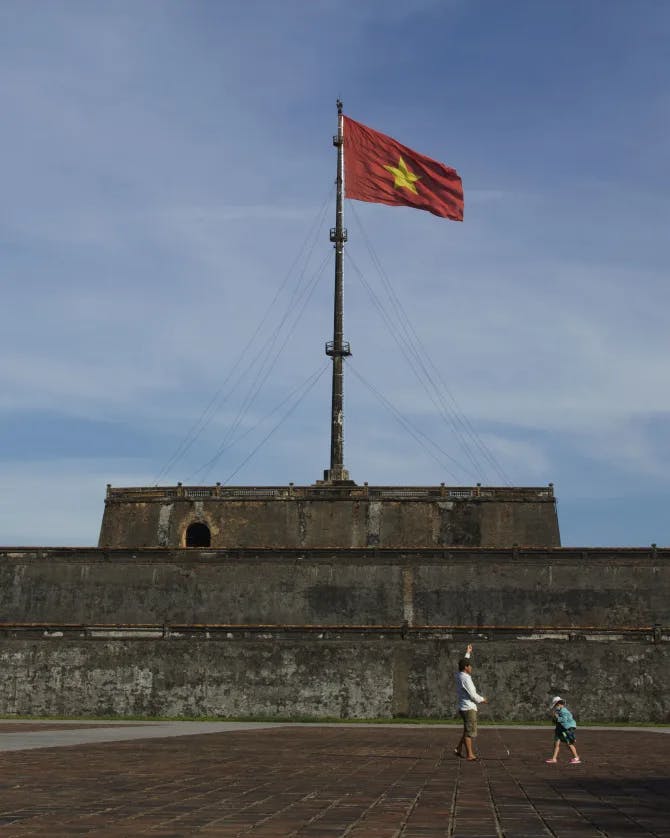 An old, military-style building with the Vietnamese flag on top.