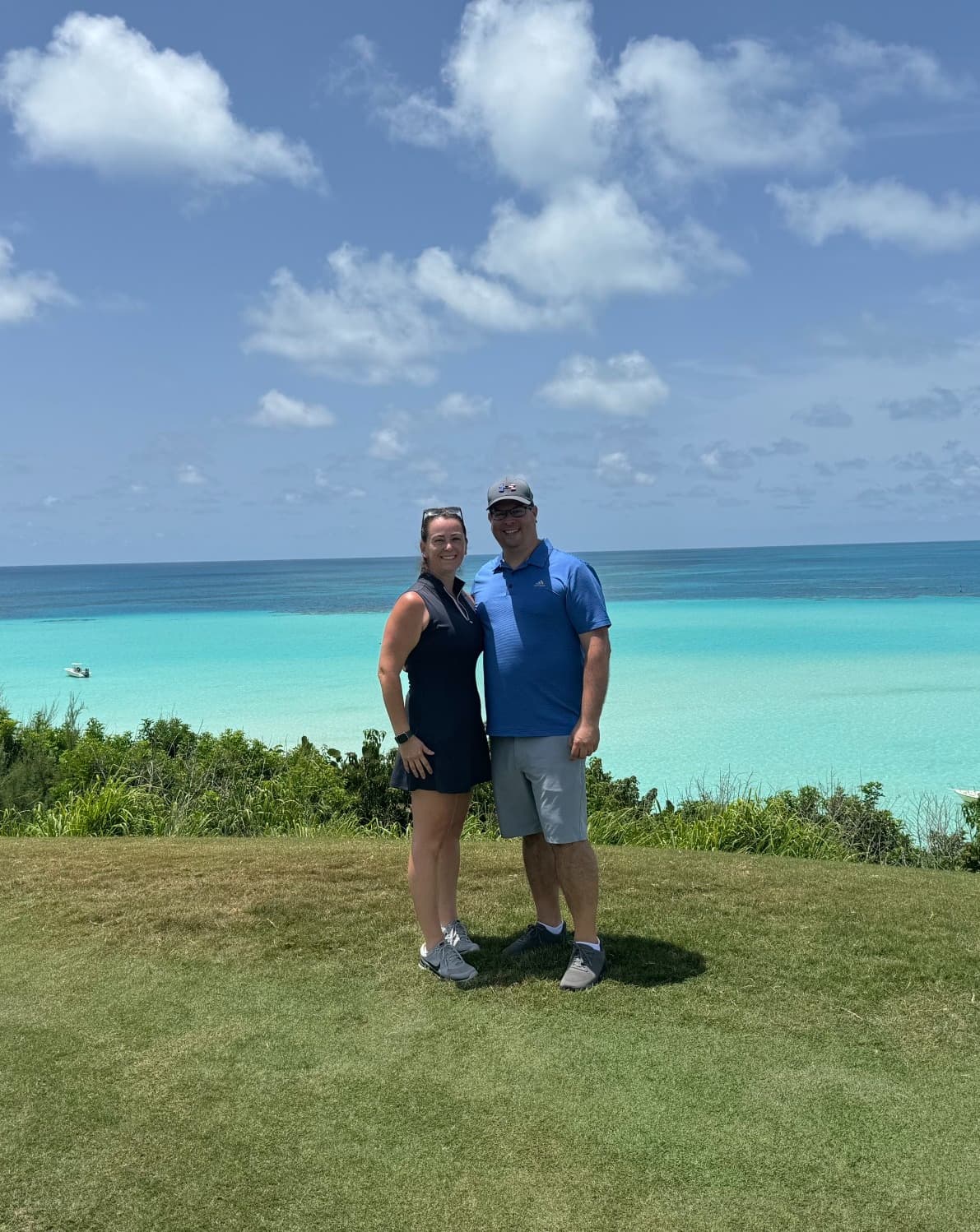 Advisor stands with their partner on a golf course at Hole 8 overlooking the Atlantic ocean.