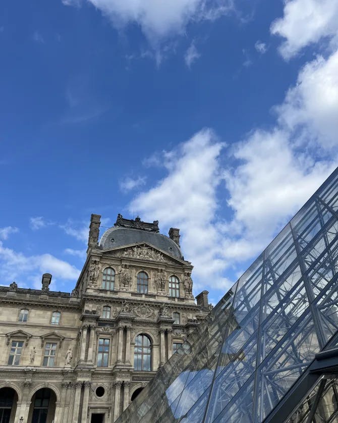 An upward angle of the Louvre on a sunny day with clouds