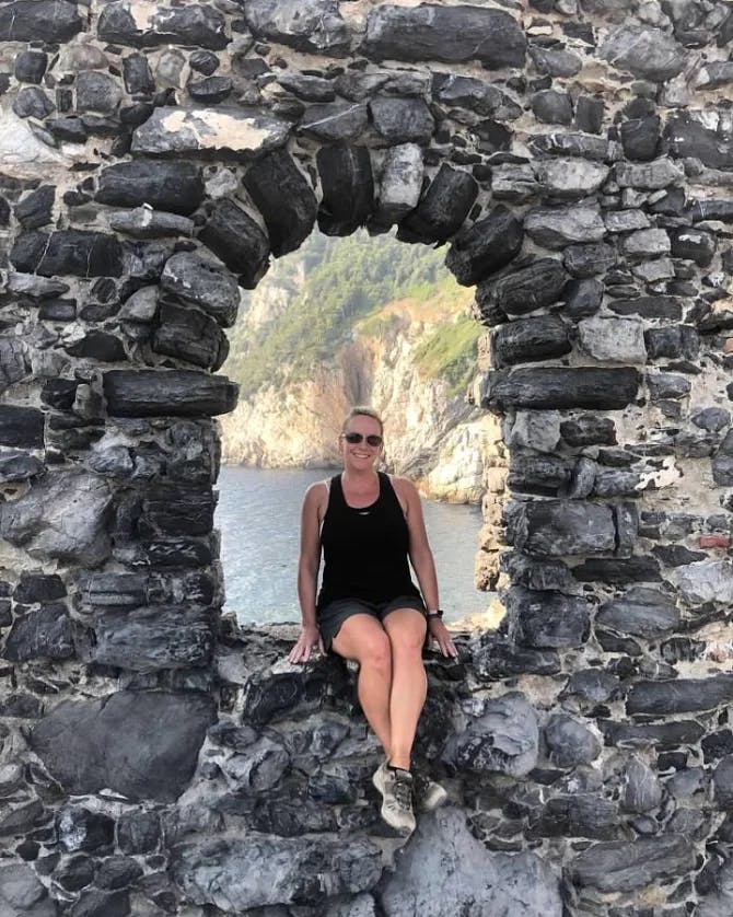 Travel advisor Shannon sitting in the hole of a rocky wall with opening with ocean view