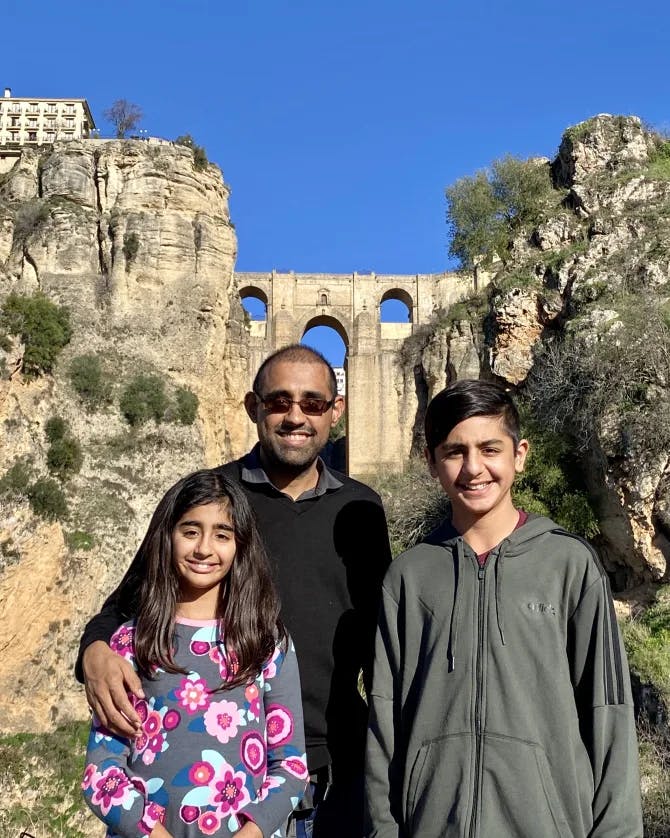 a man posing with his 2 children, girl and boy