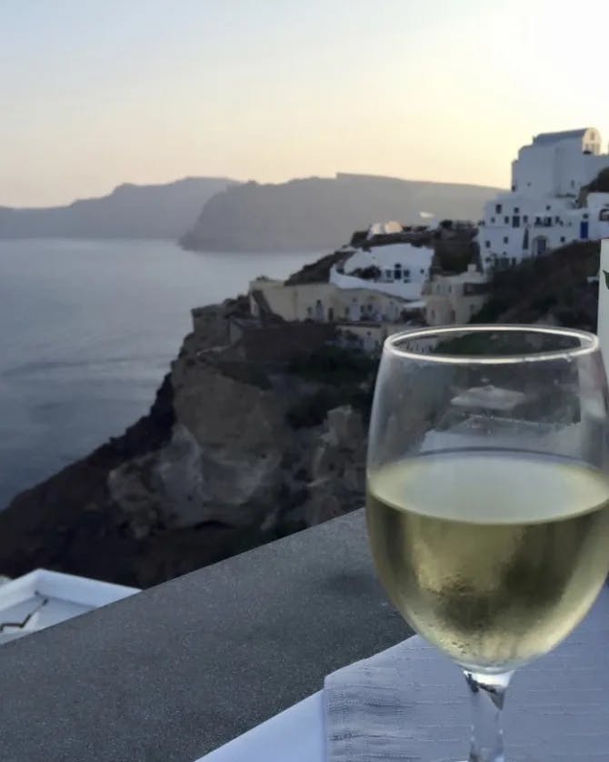 A wine glass with ocean and buildings at the back.