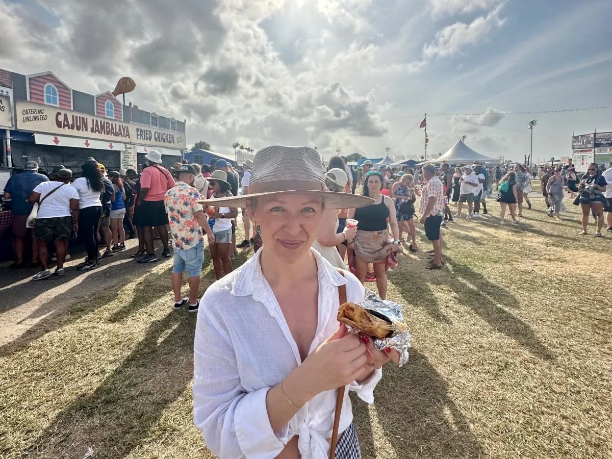 A woman holding crawfish bread with food stands behind her.