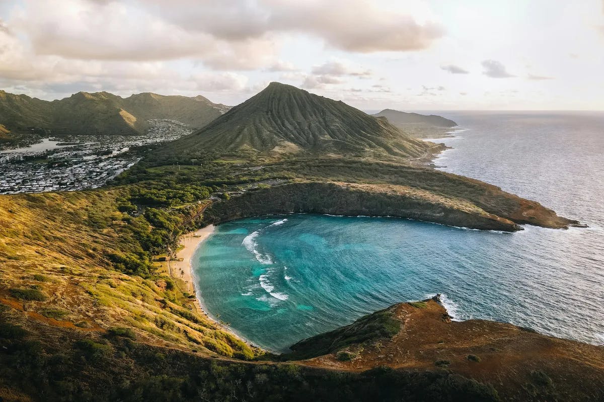 An aerial view of Hanauma Bay, with blue water encircled by green cliffs.