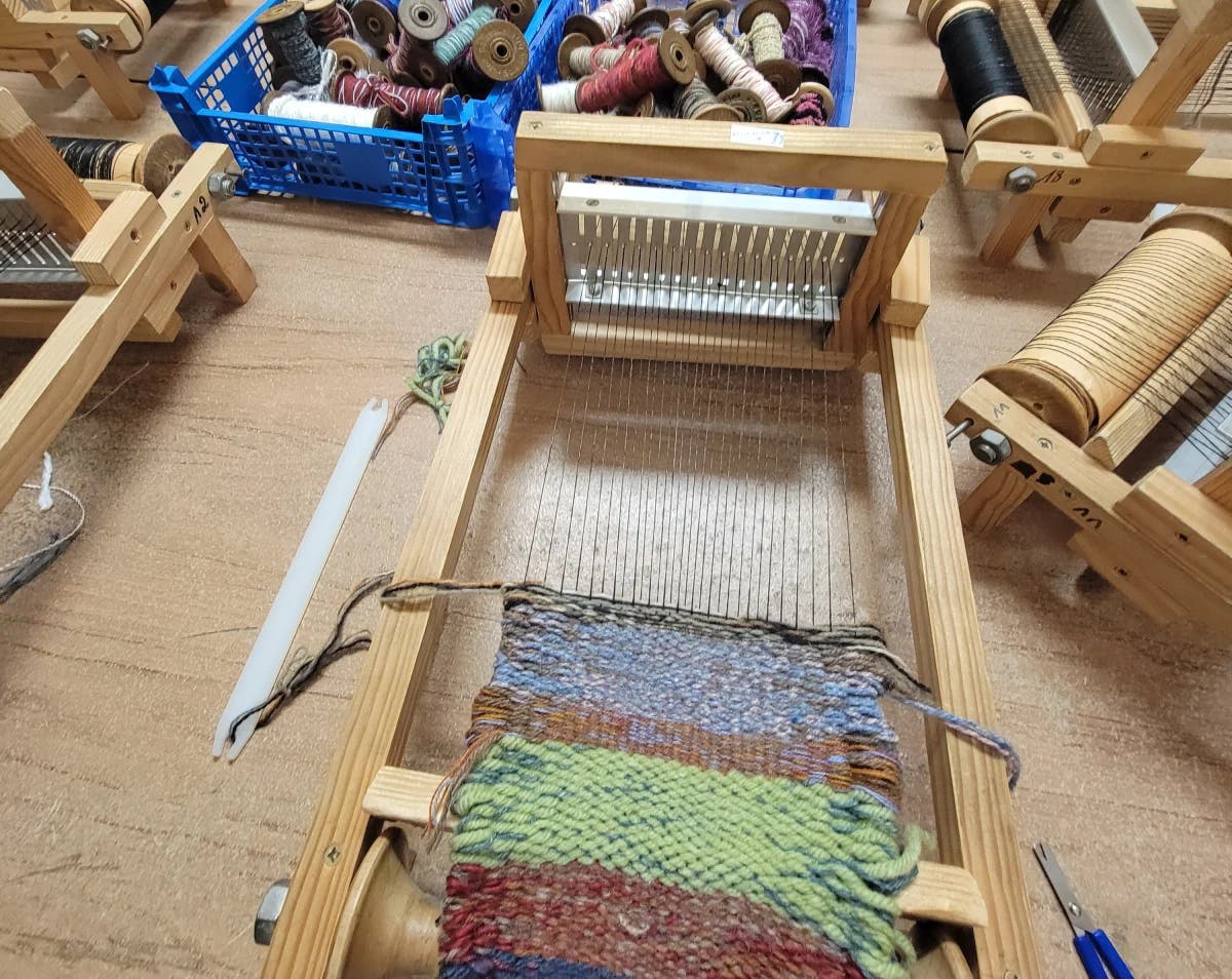 A fabric making class with small looms and colorful yarns.