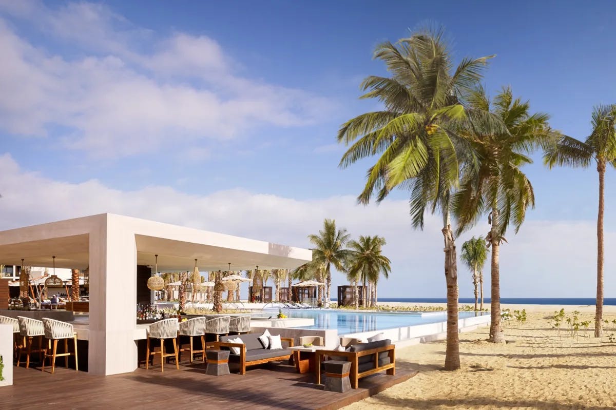 view of ocean with pool and sleek hotel bar in the foreground