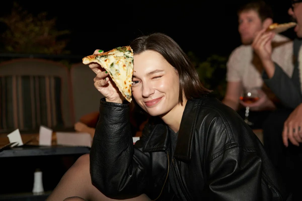 Advisor holding a slice of pizza at a restaurant.