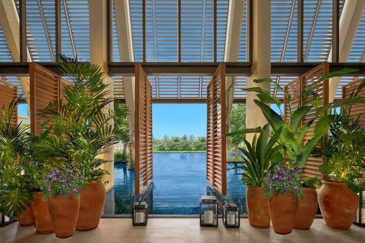 louvered doors flanked by huge terra cotta planters looking out to a water view and blue sky