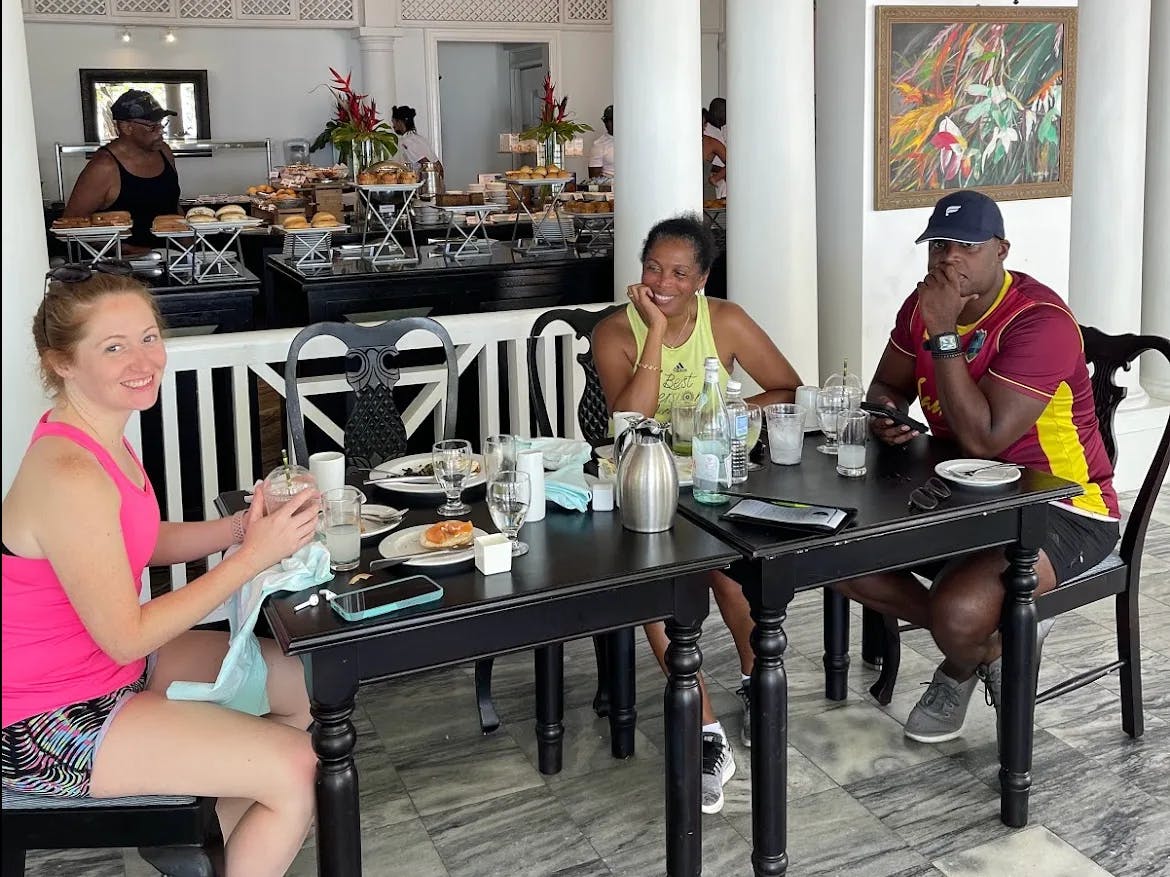 Four individuals enjoy a meal at an elegant dining table, surrounded by sophisticated decor and a buffet setup.